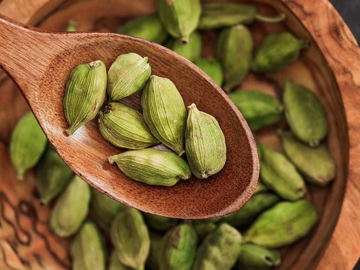 Green cardamom pods, Elettaria cardamomum, in a wooden spoon and bowl