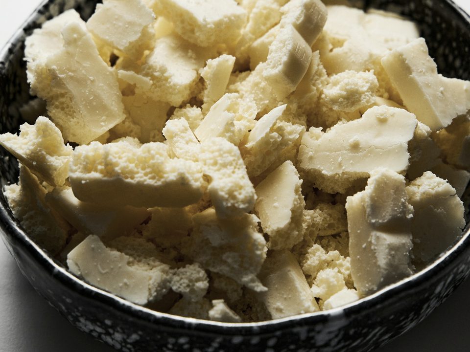 Kokum butter, hard pale ivory pieces in a dark stoneware bowl
