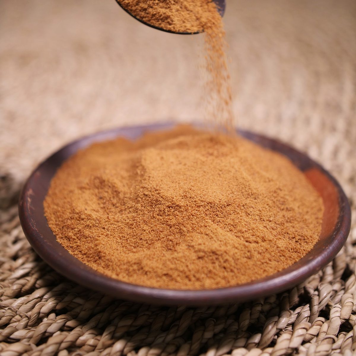Shatavari extract, a yellowish-brown powder poured from a wooden spoon into a dish