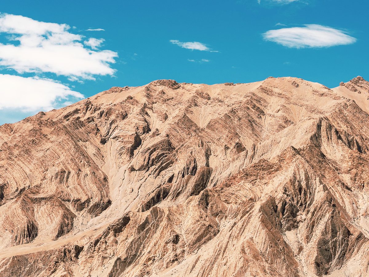 Folded rock strata under a blue sky in the Himalayas, the terrain shilajit seeps from