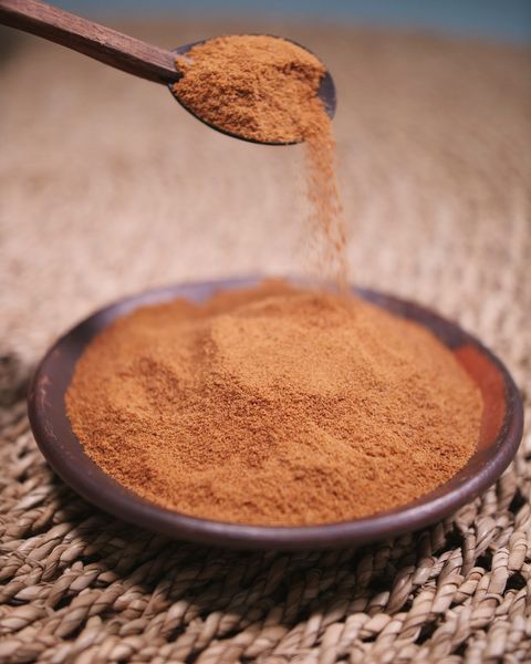 Fine botanical extract powder poured from a spoon into a dish